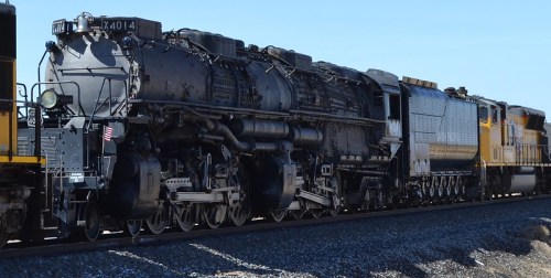 A large steam locomotive, Union Pacific 4014, stands on the tracks under a clear blue sky.