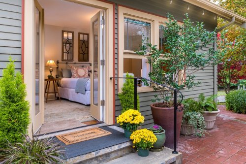 A welcoming entrance with potted plants, a doormat, and a view into a cozy, well-decorated room.