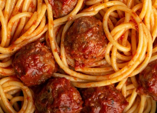 A close-up of spaghetti intertwined with meatballs in a rich tomato sauce.