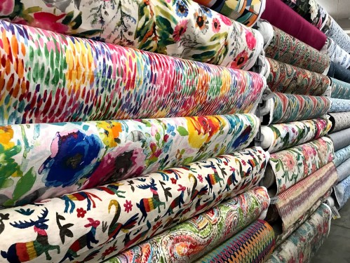 A colorful display of various patterned fabrics stacked neatly in a fabric store.