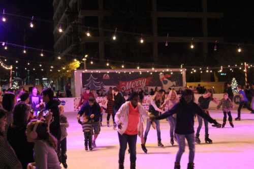 A lively outdoor ice skating rink at night, decorated with festive lights and people skating joyfully.