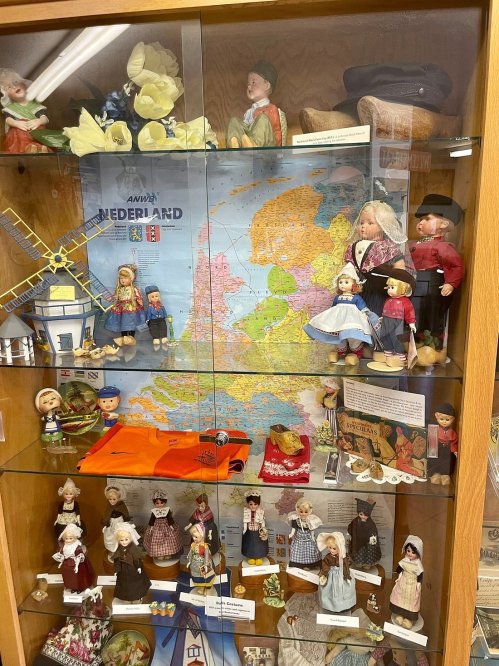 Display case featuring Dutch dolls, traditional attire, a map of the Netherlands, and cultural artifacts.