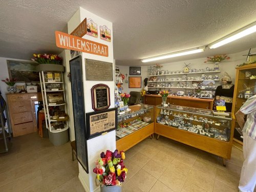 A cozy shop interior with display cases of collectibles, flowers, and a welcoming atmosphere.