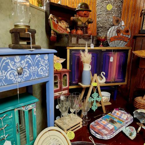 A colorful display of vintage decor items, including furniture, glassware, and seasonal decorations.