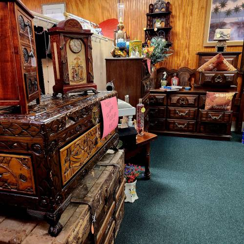 A cozy antique shop filled with intricately carved wooden furniture and decorative items, showcasing various vintage pieces.