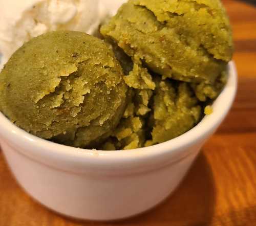 A small white bowl filled with green matcha ice cream and a scoop of vanilla ice cream on top.