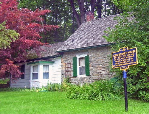 Historic John Benner House, featuring a stone and wood exterior, surrounded by lush greenery and colorful trees.