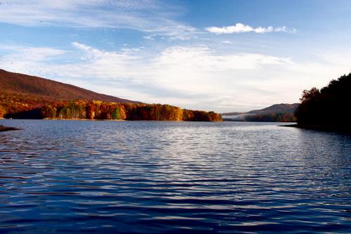 A serene lake surrounded by autumn foliage and mountains under a clear blue sky.