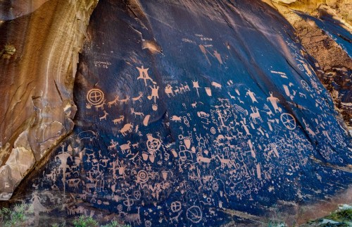 Petroglyphs on a rock face, featuring various symbols and figures, showcasing ancient artwork and cultural history.
