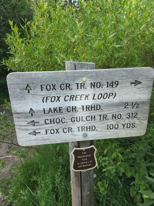 Wooden trail sign with directions to Fox Creek Loop, Lake Creek Trailhead, and Chocolate Gulch Trail.