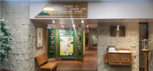 Interior of the Jackson Lake Information Center, featuring informational displays and a welcoming sign.