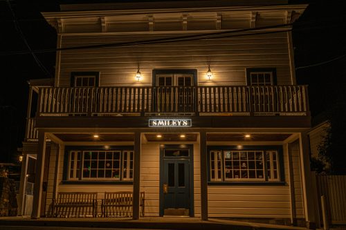 A well-lit building at night with a sign reading "Smiley's" and a bench in front.