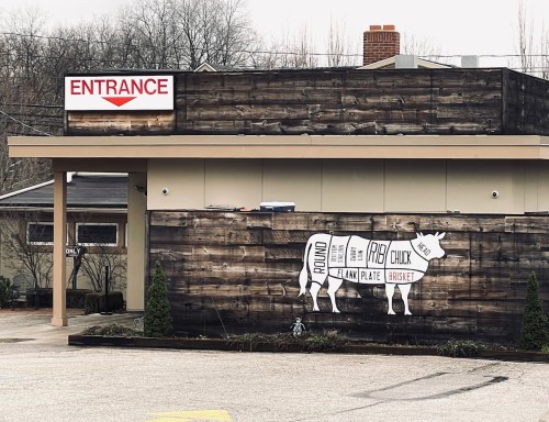 A rustic building exterior with a cow graphic showing meat cuts, labeled with "Entrance" above.