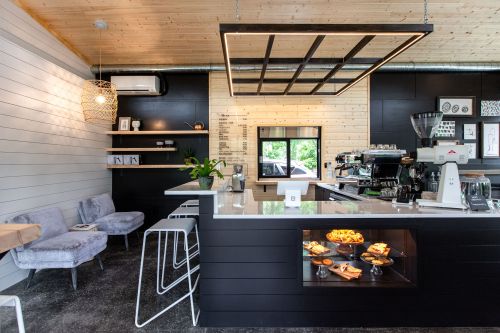 Modern café interior featuring a sleek black counter, cozy seating, and a bright, airy atmosphere.