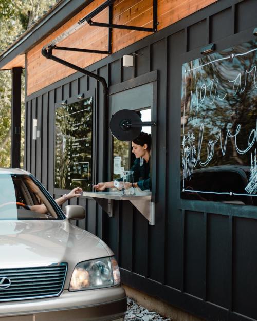 A car at a drive-thru window where a person hands over a payment to a staff member inside.