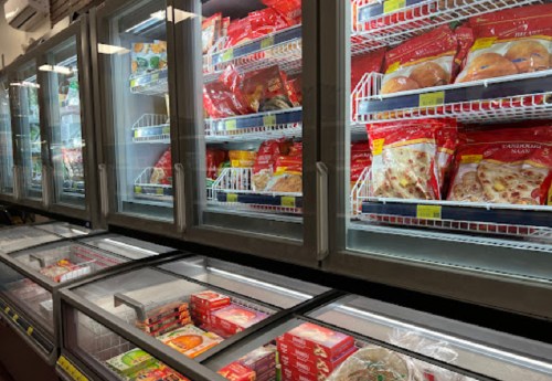 Frozen food aisle with multiple glass-front freezers filled with colorful packaged meals and snacks.