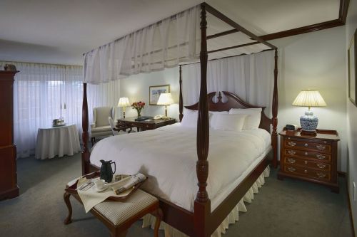 A cozy hotel room featuring a four-poster bed, elegant furnishings, and soft lighting.