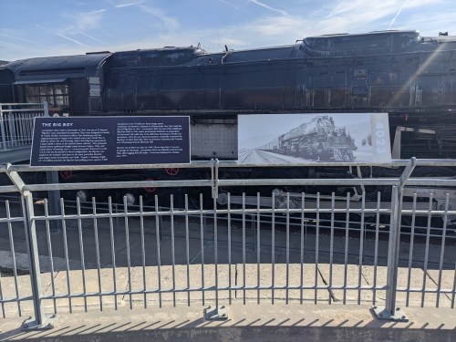 A large black steam locomotive, "The Big Boy," displayed with informational signs and a railing in front.