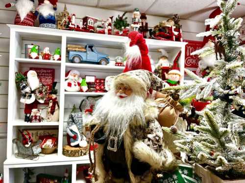 A festive display featuring a Santa figure among holiday decorations, including trees, ornaments, and a vintage truck.