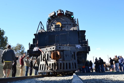 A large steam locomotive, number 4014, stands on the tracks with a crowd of people gathered nearby.