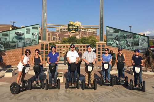 A group of eight people on segways, posing in front of a historical display at the Heritage Trail.