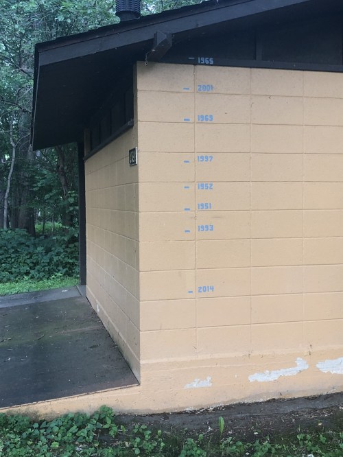 A yellow wall with blue markings indicating years from 1933 to 2014, surrounded by greenery.