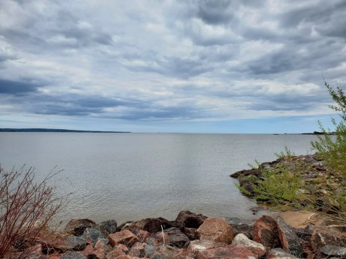 A calm lake scene with rocky shorelines and overcast skies, reflecting a tranquil atmosphere.