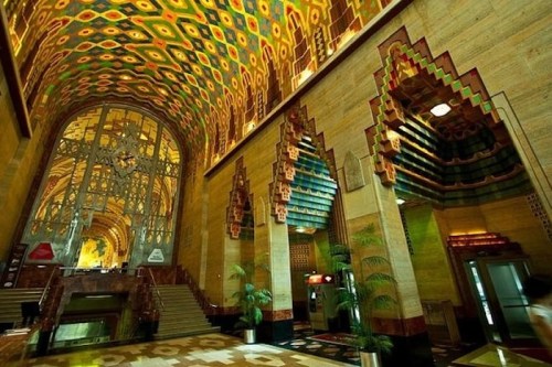 A grand interior with colorful patterned ceilings, ornate arches, and elegant staircases in a luxurious building.