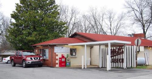 A red truck parked outside a small barbecue restaurant with a red roof and a sign reading "Marie's Barbecue."