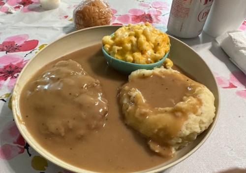 A plate with two servings of mashed potatoes topped with gravy, alongside a bowl of macaroni and cheese.