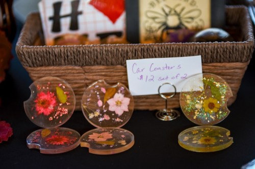 A basket with decorative car coasters featuring flowers and glitter, priced at $12 for a set of two.