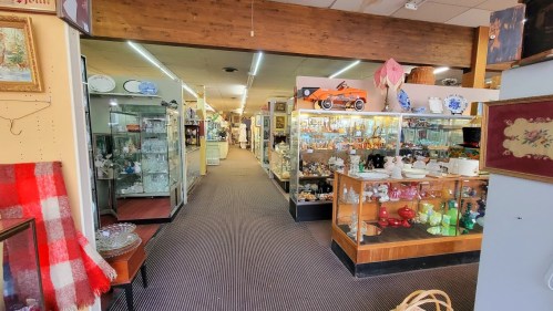 A spacious antique shop aisle lined with glass display cases filled with various collectibles and vintage items.