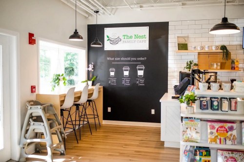 A cozy café interior featuring a menu wall, seating area, and a display of magazines and coffee supplies.