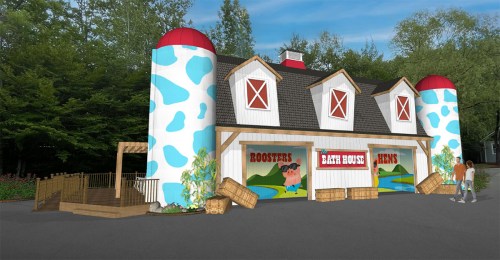 A colorful barn-themed building with silos, featuring signs for "Roosters" and "Hens," surrounded by greenery.
