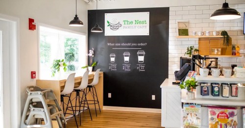 Interior of The Nest Family Café featuring seating, a coffee bar, and a wall sign about drink sizes.