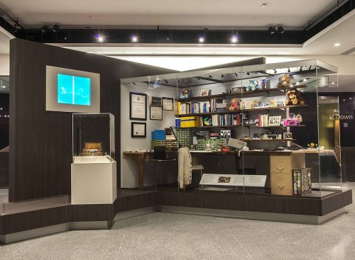 A modern exhibit showcasing various artifacts, books, and memorabilia in a glass display case.