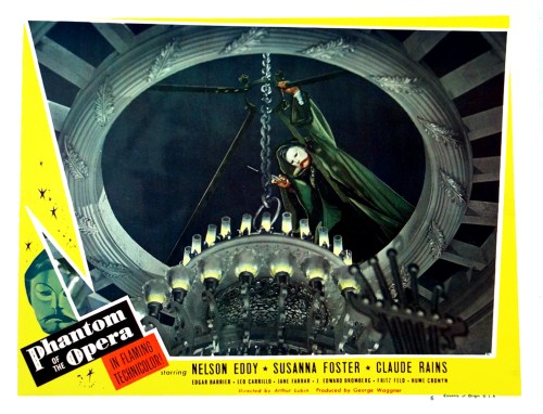 A dramatic scene from "Phantom of the Opera," featuring a masked figure hanging above a chandelier.