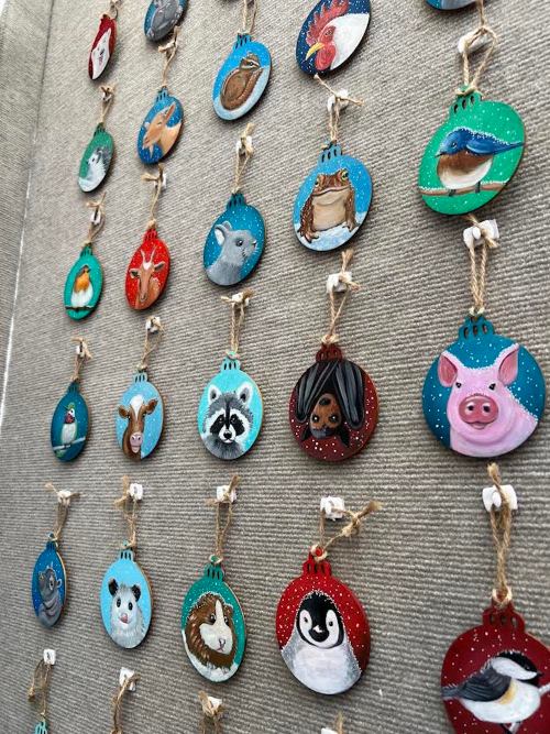 A display of hand-painted animal ornaments hanging on a wall, featuring various colorful designs.