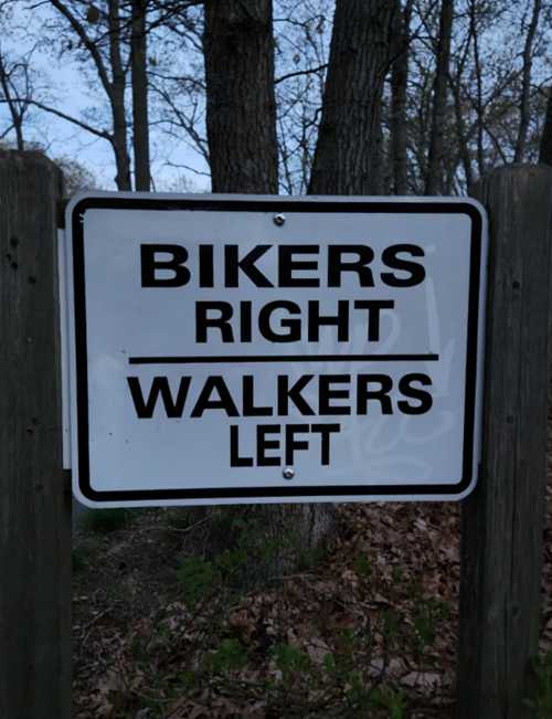 Sign indicating directions: "Bikers Right, Walkers Left" in a wooded area.