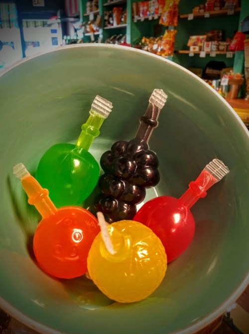 A colorful assortment of candy bottles in a bowl, featuring green, black, red, orange, and yellow shapes.