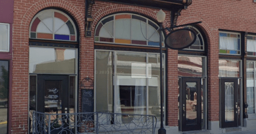 A brick building with large arched windows and a decorative sign, featuring colorful stained glass accents.