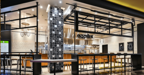 Modern restaurant interior featuring a stylish counter and seating area, with a prominent "eggshut" sign.