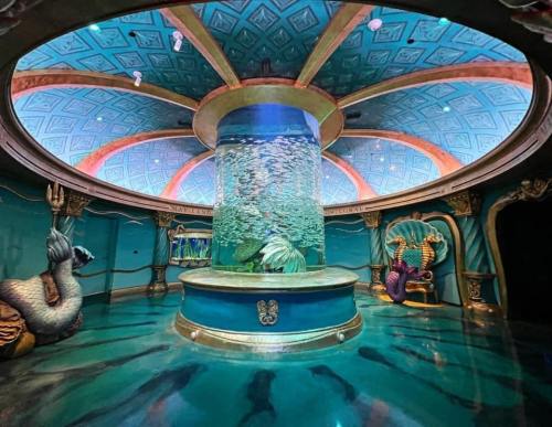 A vibrant underwater-themed room featuring a large fish tank, ornate decorations, and colorful murals.