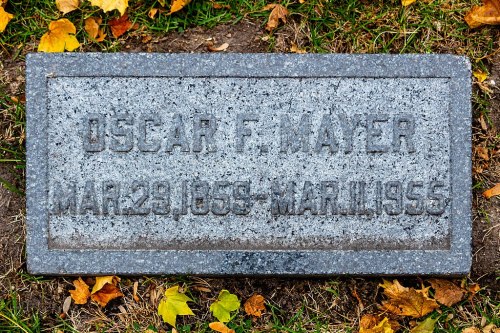 Gravestone of Oscar F. Mayer, marked with his name and dates: March 29, 1859 - March 1915. Surrounded by grass and leaves.