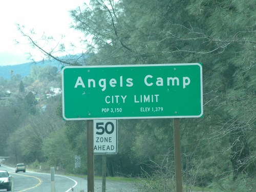 Green city limit sign for Angels Camp, noting population 3,150 and elevation 1,379 feet, with a 50 mph speed zone ahead.