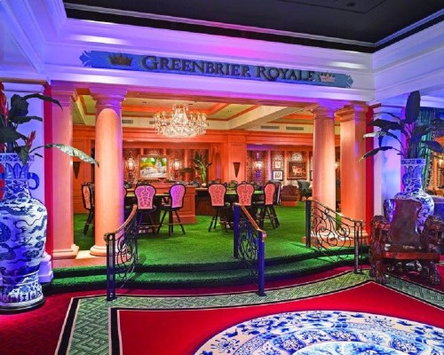 Elegant interior of the Greenbrier Royale, featuring vibrant decor, lush greenery, and ornate furnishings.