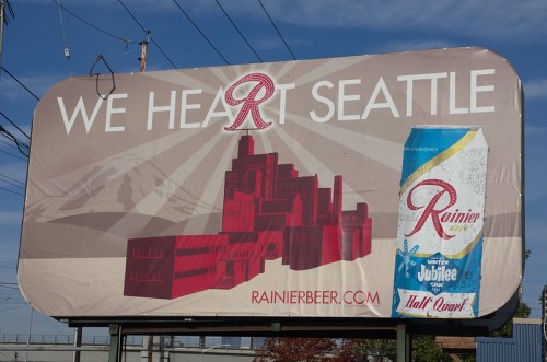 Billboard featuring "We Heart Seattle" with a graphic of the city skyline and a Rainier beer can.