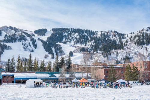 A snowy landscape with a mountain backdrop, featuring a crowd of people with bikes and tents in a winter event.