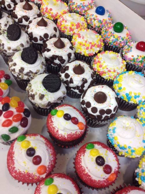 A colorful assortment of decorated cupcakes with various toppings, including sprinkles, candies, and cookies.