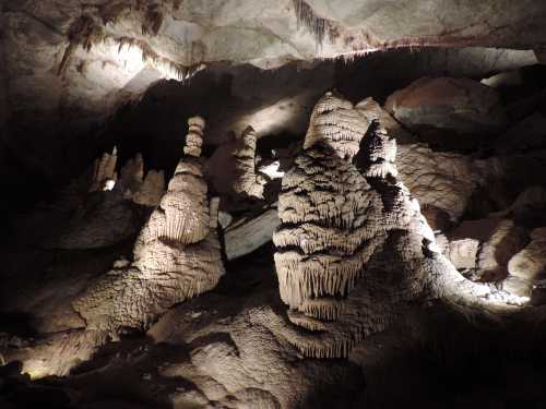 Stalactites and stalagmites in a dimly lit cave, showcasing unique rock formations and textures.